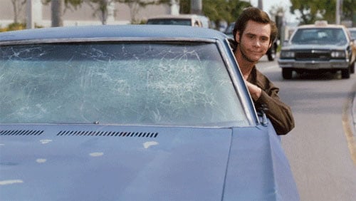 Ace Ventura peering out of the window of his car